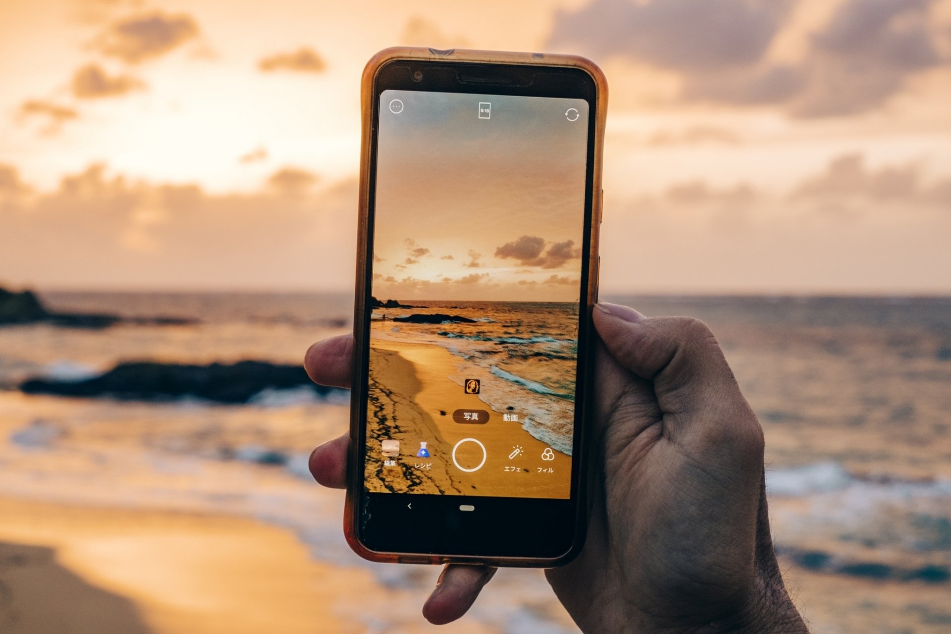 スマートフォンで海辺の夕焼けを撮影