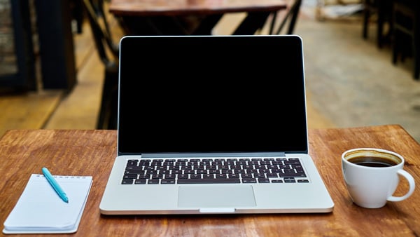 カフェのテーブルの上にメモ帳、PC、コーヒー
