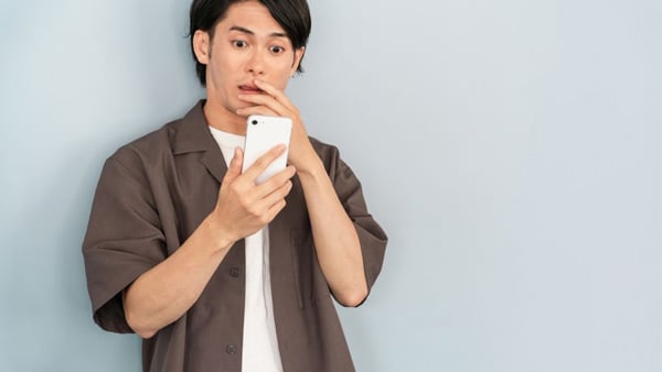 スマートフォンを見て何かに驚く男性