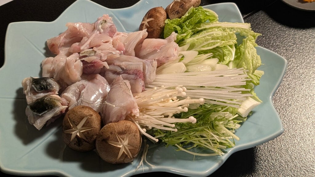 fugu cooked in a shallow pan with vegetables in a pot