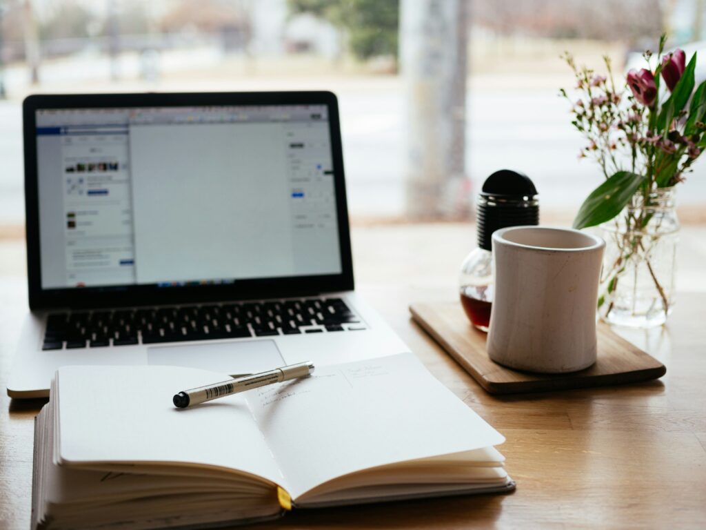 カフェでノートパソコンとノートを開きながら勉強している様子